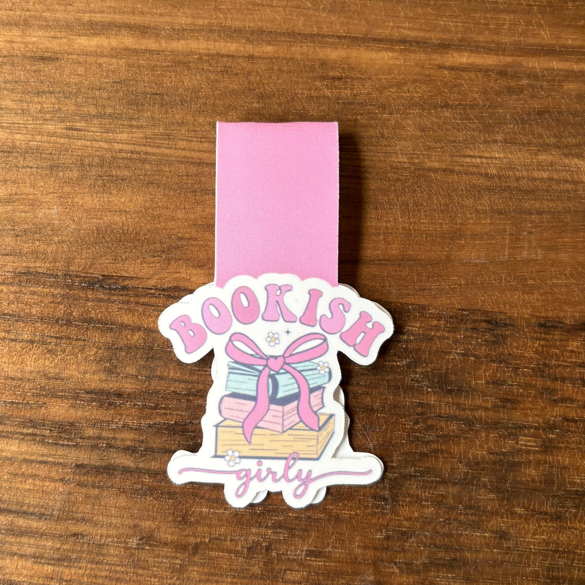 magnetic bookmark with 'Bookish girly' design on a pink ribbon against a wooden background