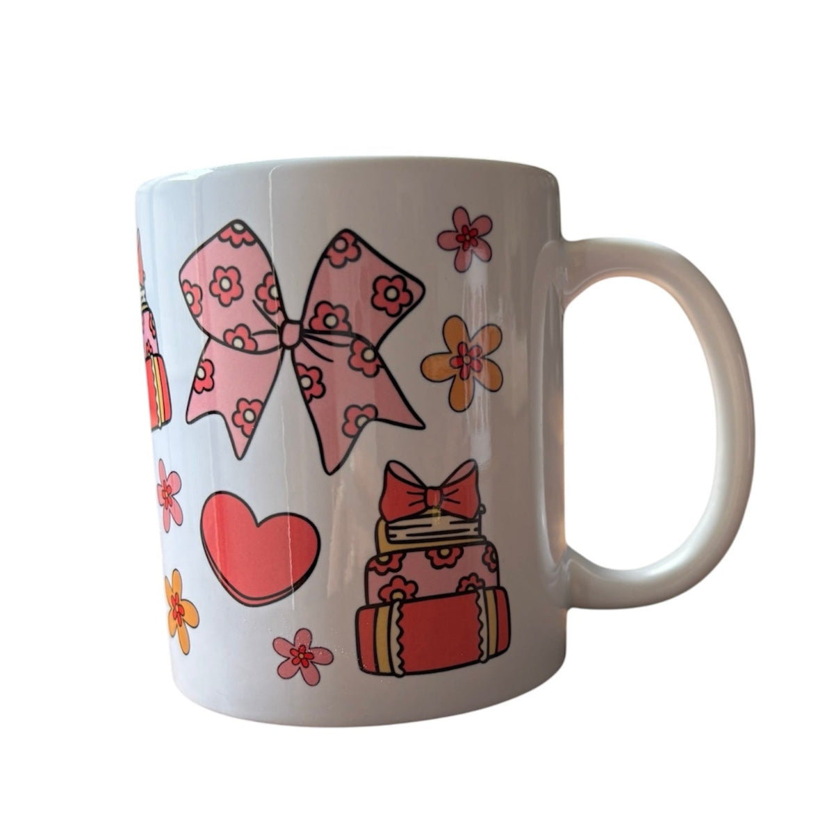 White mug with pink bow, heart, and flower designs on a white background