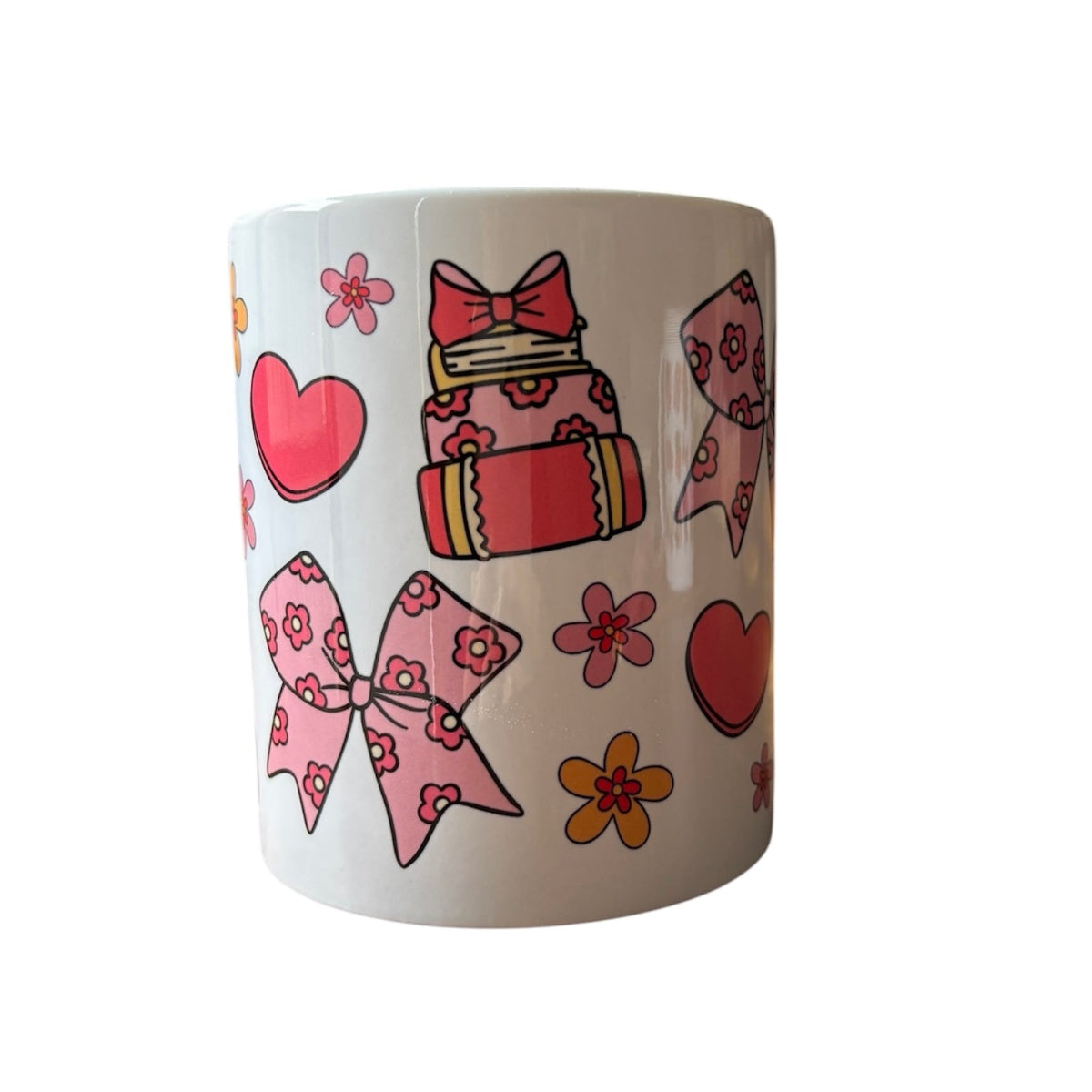 White mug with colorful cake, bow, and heart designs on a white background