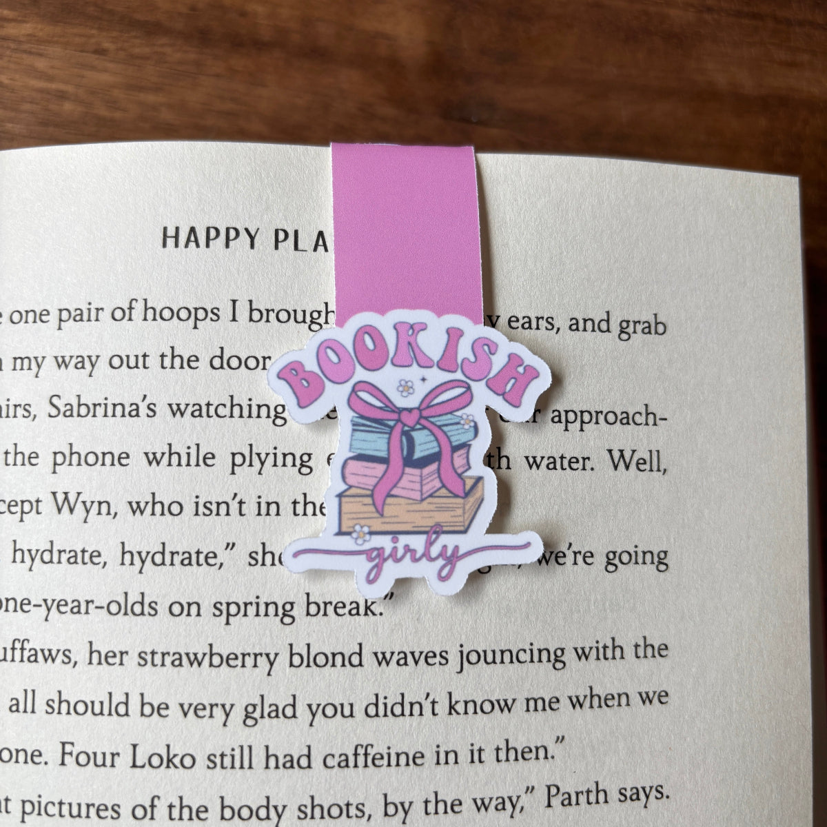 Pink 'bookish girly' bookmark on a book with text.