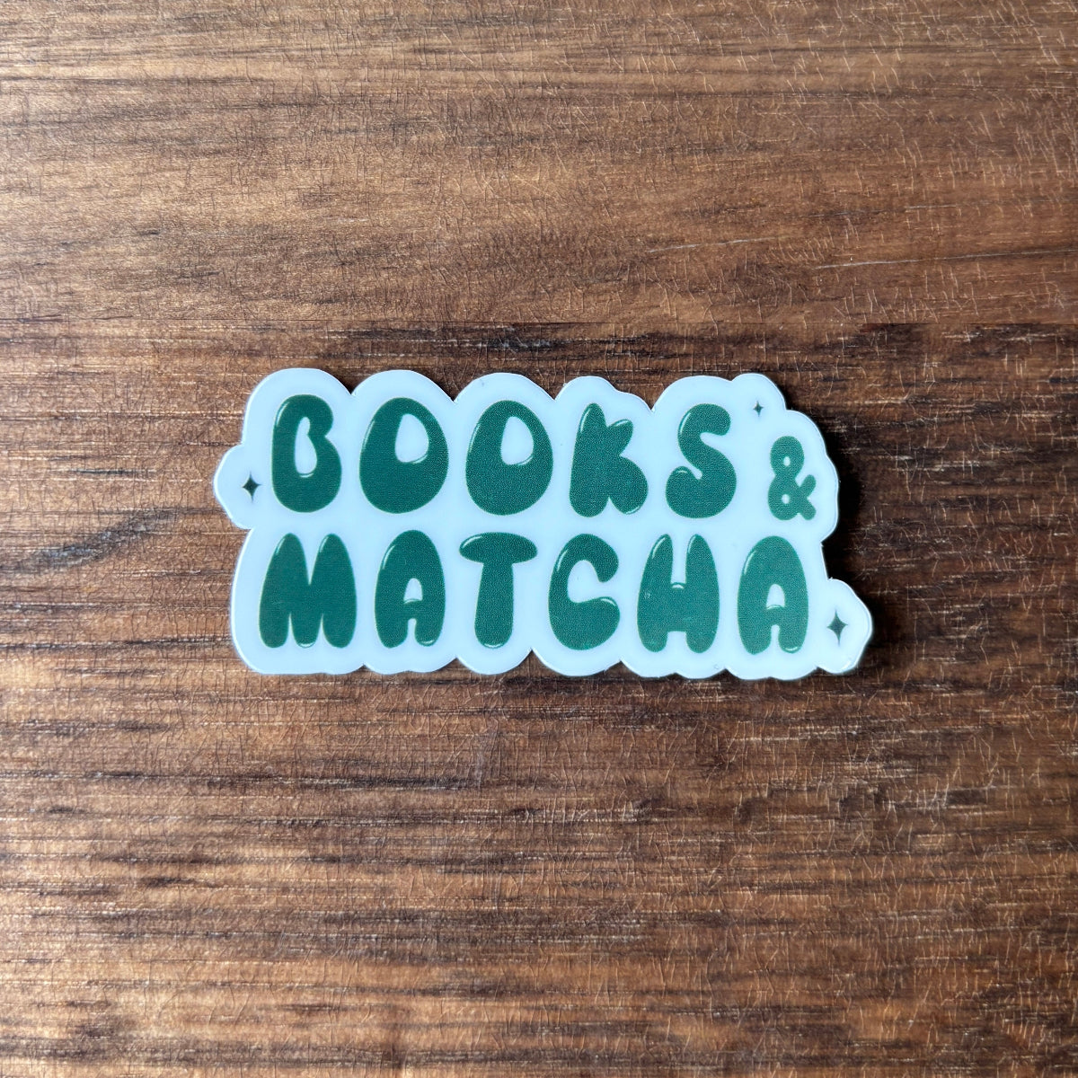 Sticker with 'BOOKS & MATCHA' text on a wooden surface