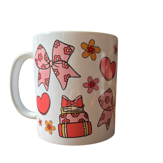 White mug with pink bows, hearts, and flowers on a white background
