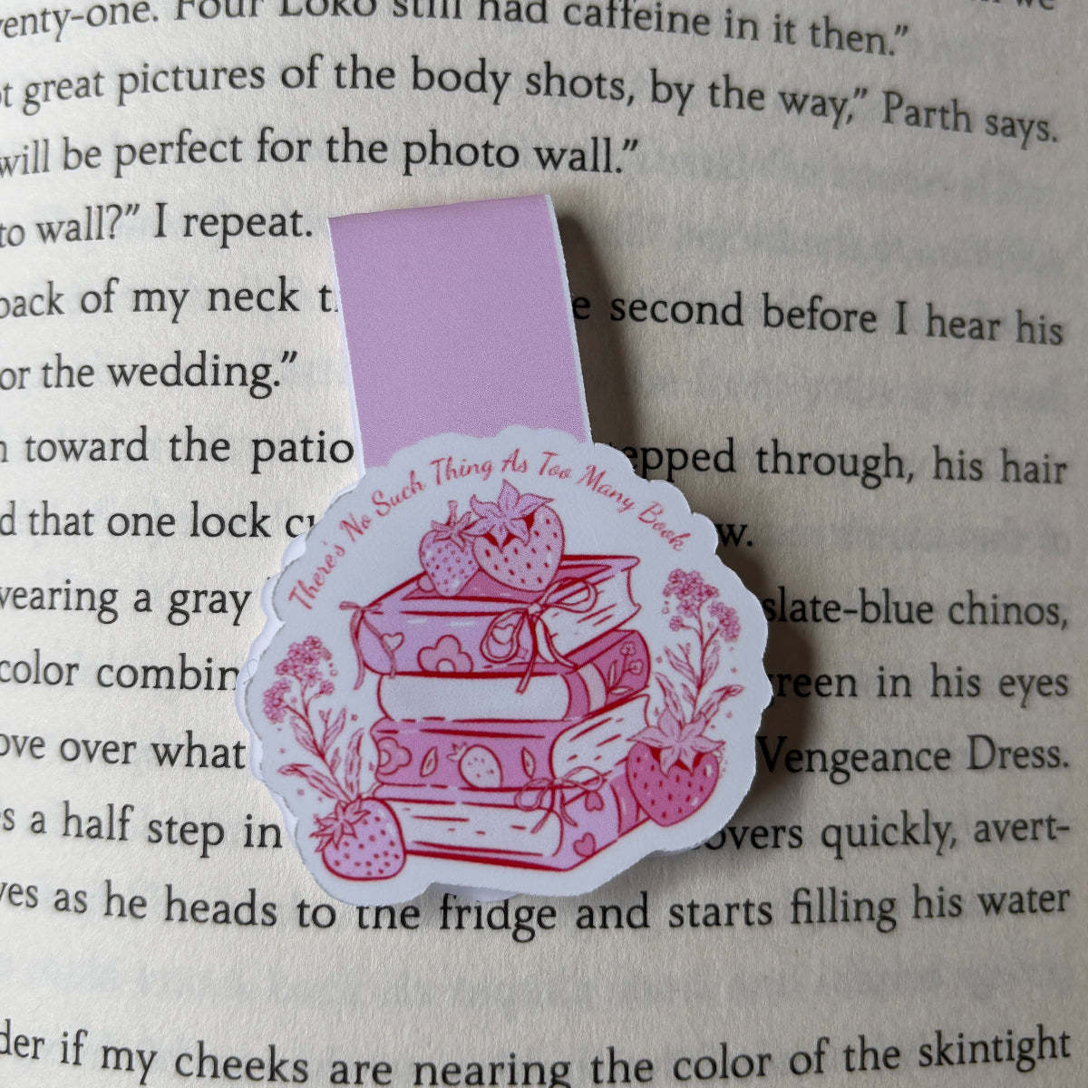 Pink bookmark with a design of books and strawberries on a book page.