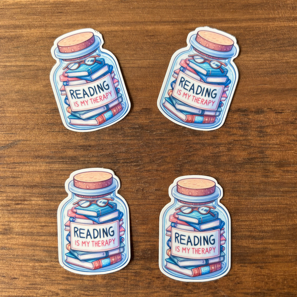 Four 'Reading is my therapy' sticker on a wooden surface