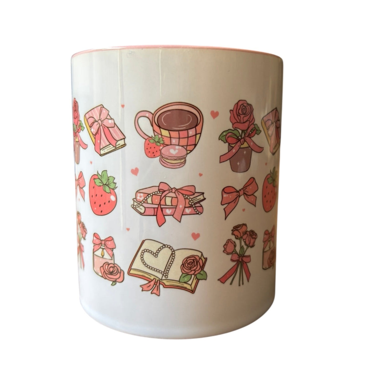 White mug with decorative illustrations of bows, books, and strawberries on a white background